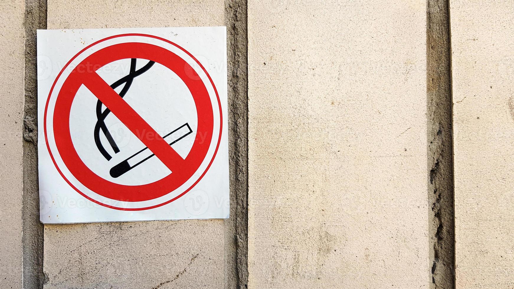 étiquette non fumeur signe rond dans la ville. des panneaux non-fumeurs qui suivent les murs de toutes les zones pour limiter la zone fumeurs. panneau rouge et noir avec un fond texturé en pierre grise - non fumeur photo