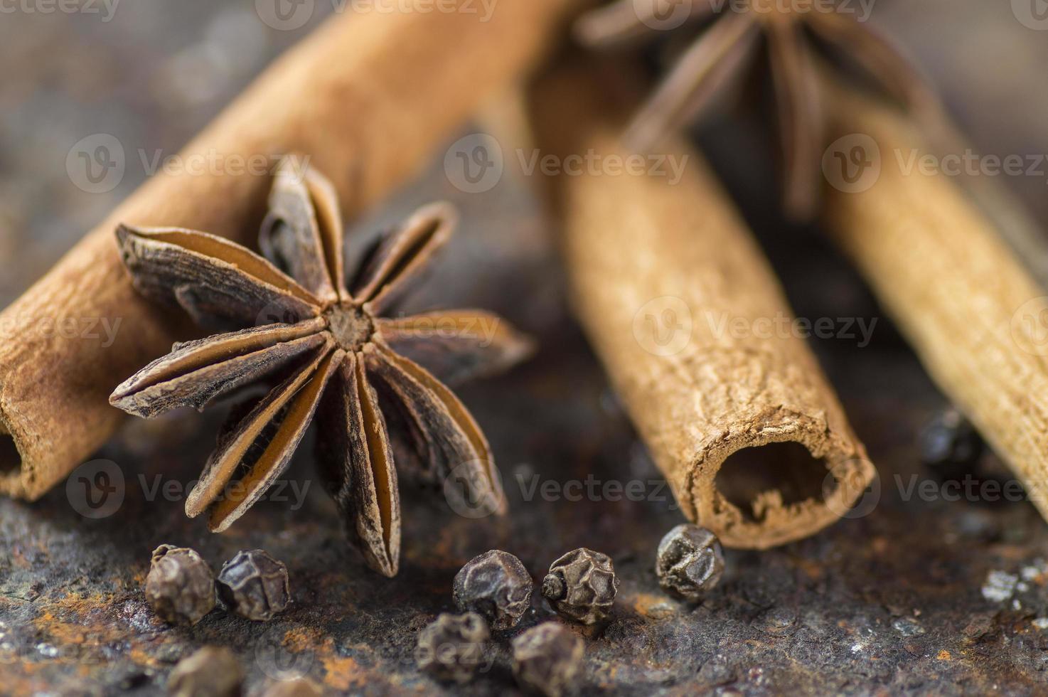 bâtons de cannelle, étoiles d'anis et grains de poivre noir sur fond texturé photo