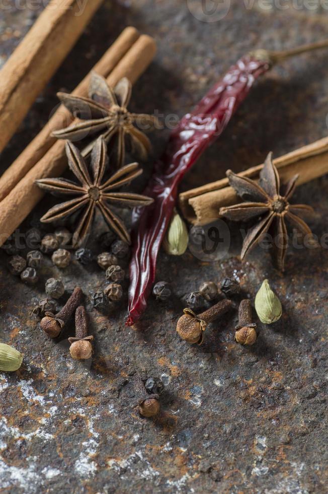 épices et herbes. ingrédients de la nourriture et de la cuisine. bâtons de cannelle, étoiles d'anis, grains de poivre noir, piment, cardamome et clous de girofle sur fond texturé photo