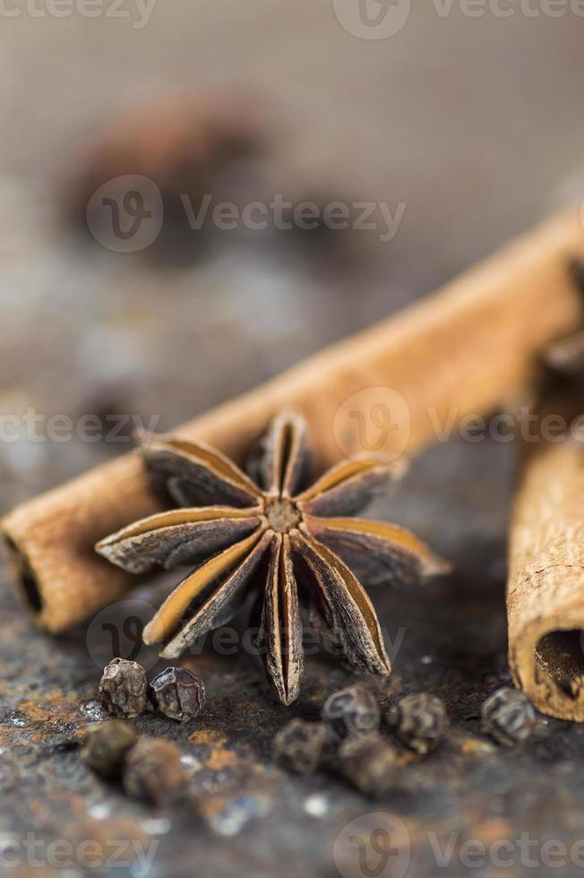 bâtons de cannelle, étoiles d'anis et grains de poivre noir sur fond texturé photo