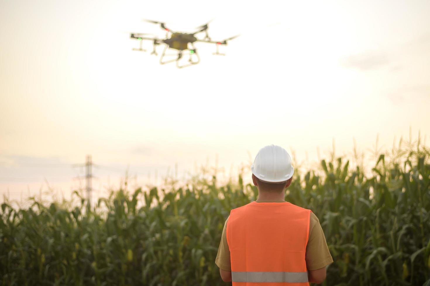 ingénieur masculin contrôlant la pulvérisation d'engrais et de pesticides par drone sur les terres agricoles, les innovations de haute technologie et l'agriculture intelligente photo