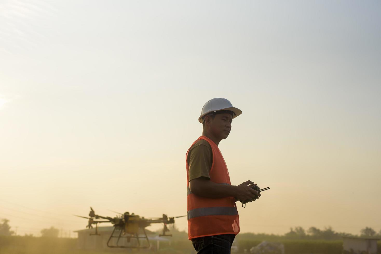 ingénieur masculin contrôlant la pulvérisation d'engrais et de pesticides par drone sur les terres agricoles, les innovations de haute technologie et l'agriculture intelligente photo