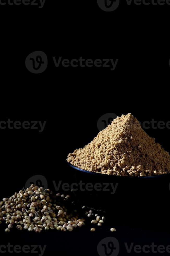poudre de coriandre et graines de coriandre sur fond noir photo
