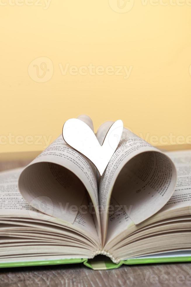 un livre ouvert avec un coeur en bois sur la table. concept d'amour pour la lecture, les livres. bibliothèque, éducation. gros plan de l'espace de copie photo