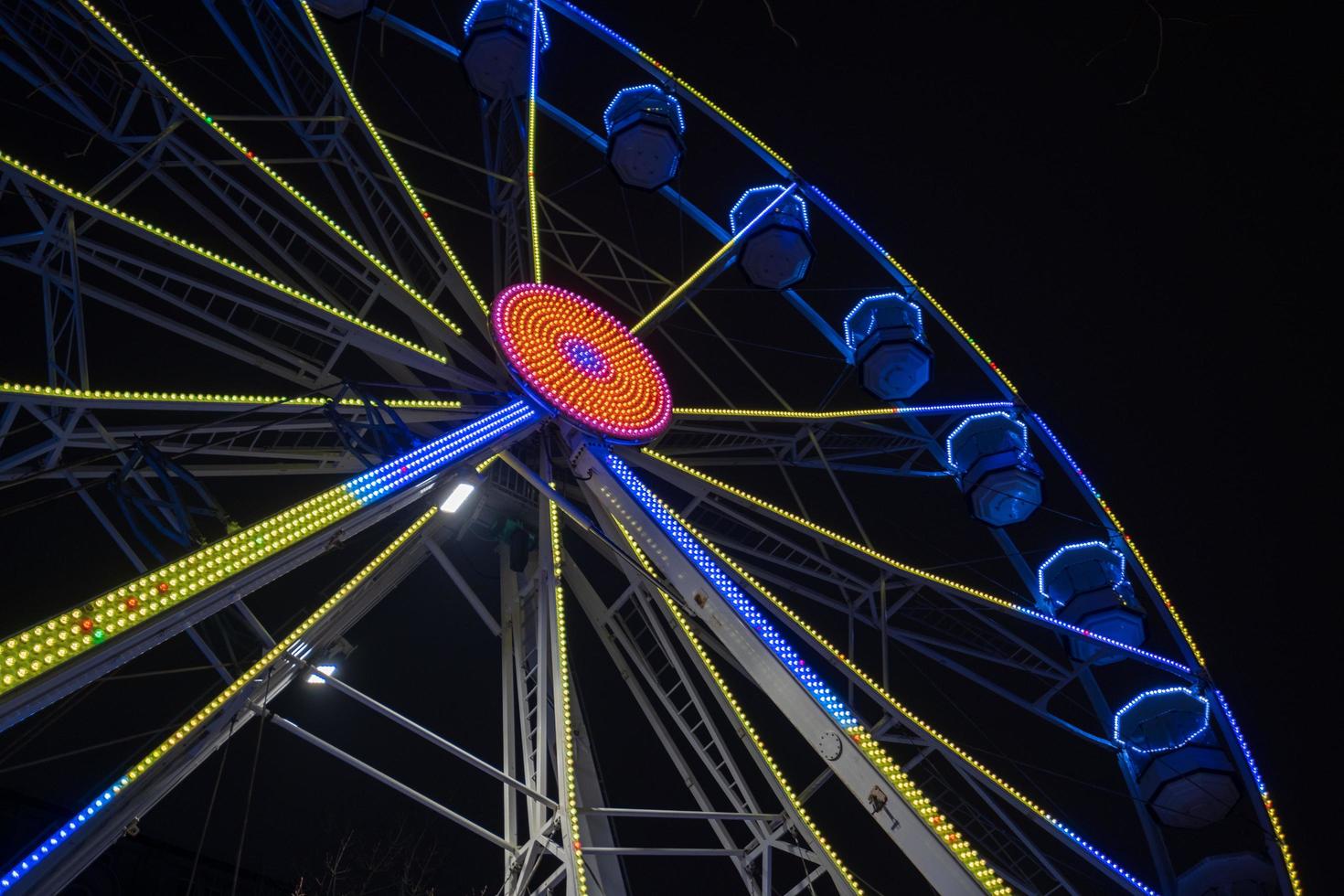 grande roue magnifiquement illuminée la nuit à leeds par la mairie de la ville. photo