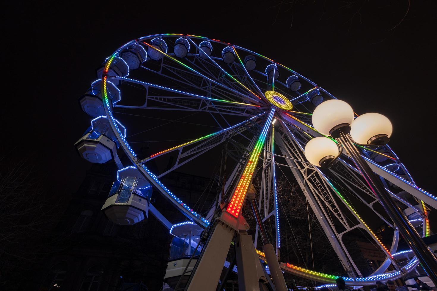 grande roue magnifiquement illuminée la nuit à leeds par la mairie de la ville. photo