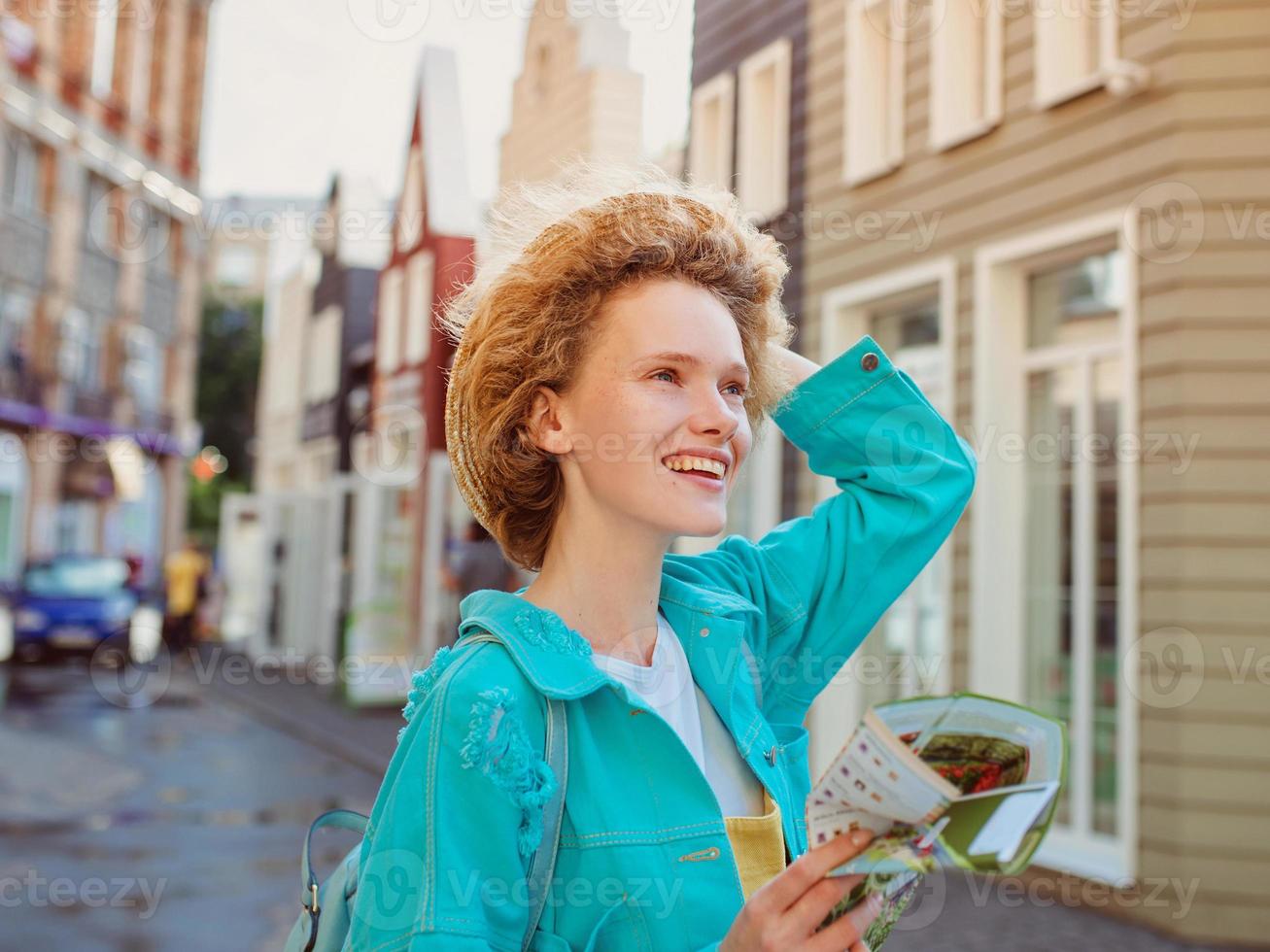 portrait de jeune femme rousse au chapeau de paille et avec sac de voyage avec carte papier voyage en europe de l'ouest. photo de voyage et lifestyle