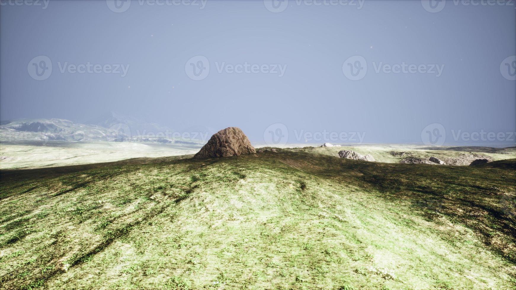 grande pierre de sable et fond de colline d'herbe verte photo