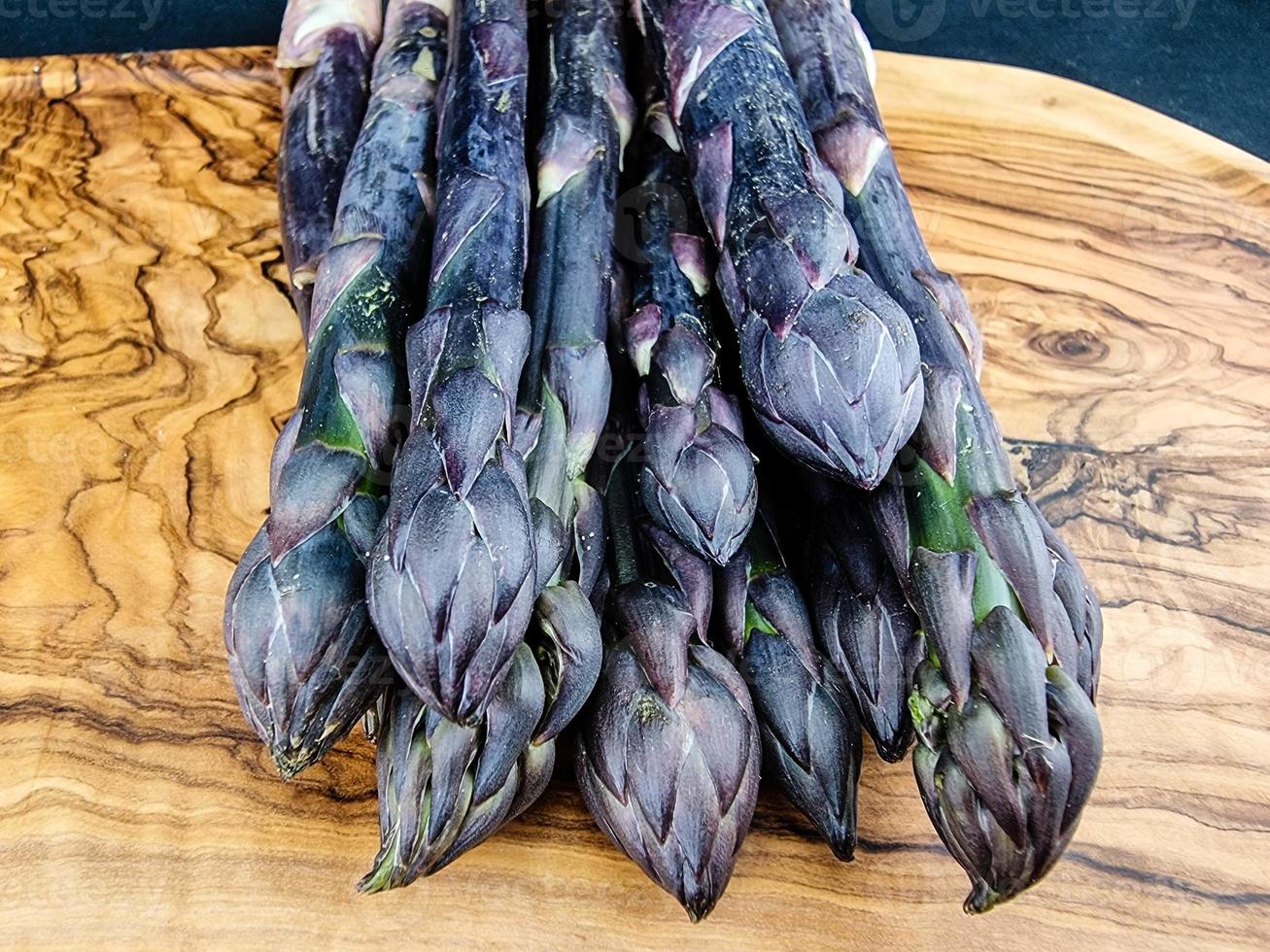 Purple Asparagus officinalis un légume de saison sur bois d'olivier photo