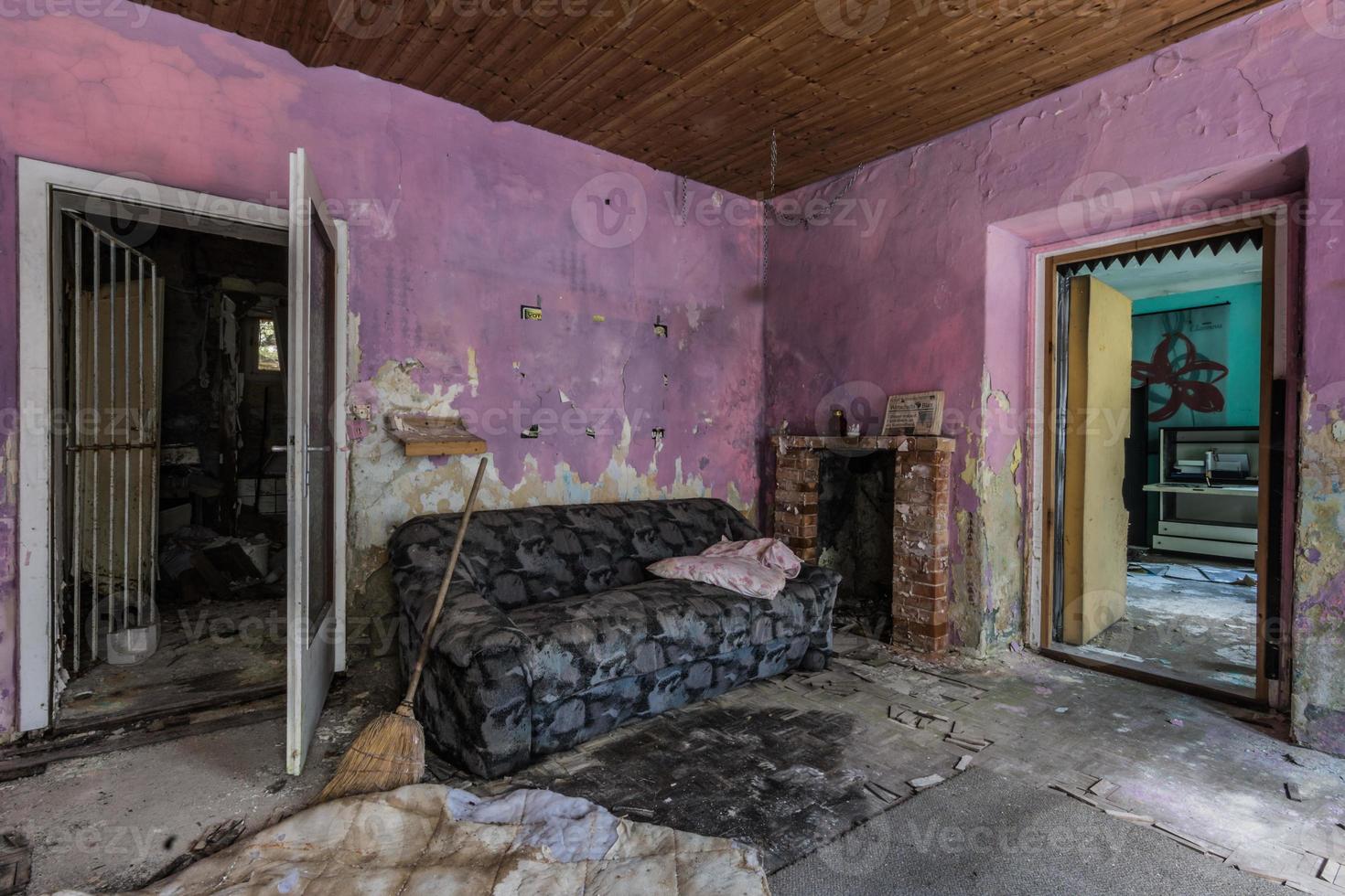 chambre abandonnée avec balai et canapé aux couleurs violettes sur le mur photo
