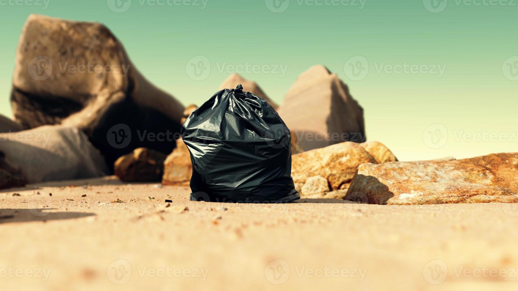 sac poubelle en plastique noir plein de déchets sur la plage photo