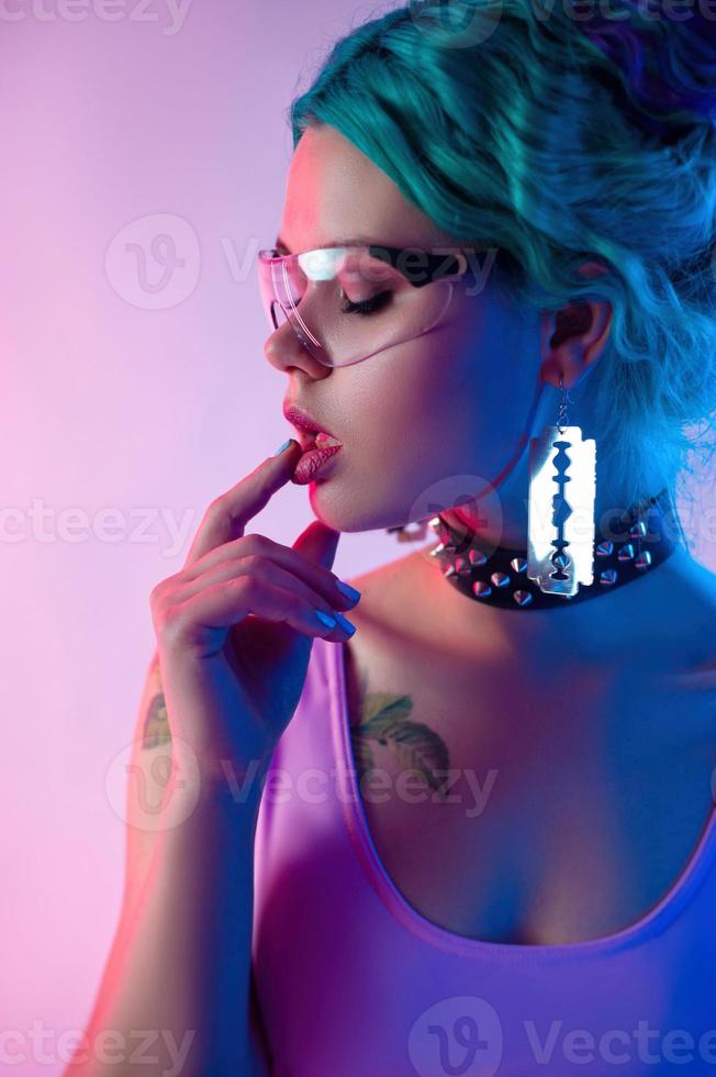 portrait d'une femme brillante aux cheveux bleus dans des verres transparents à la lumière du néon photo