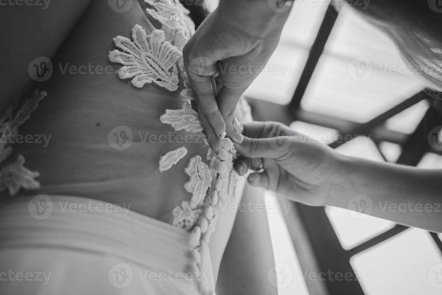 maman boutonne la robe de mariée de la mariée photo