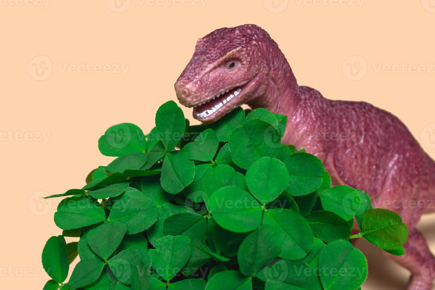 st. patrick's day joyeux dinosaure, un bouquet de trèfle dans un seau et des pièces d'or sur fond beige. gros plan de l'espace de copie photo