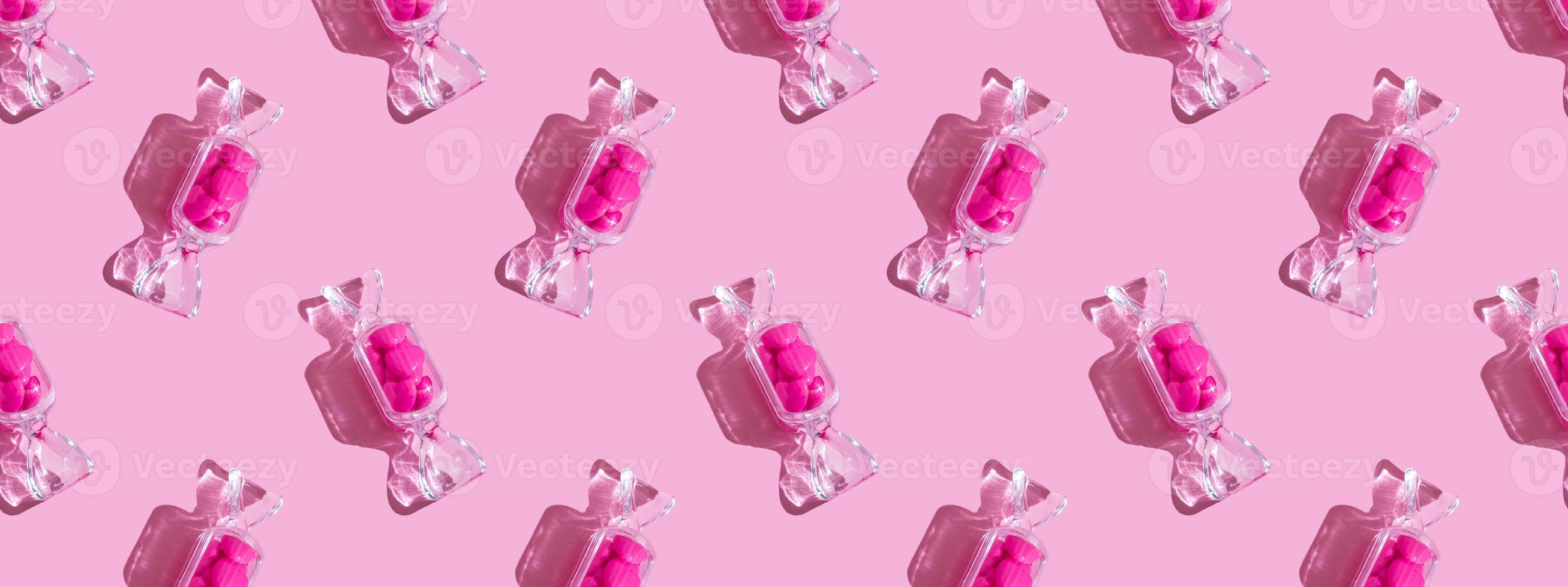 boîte transparente en forme de bonbon avec des sucettes au coeur doux avec une ombre dure sur l'espace de copie de fond rose. le concept de la saint valentin, fête des mères. bannière. schéma photo