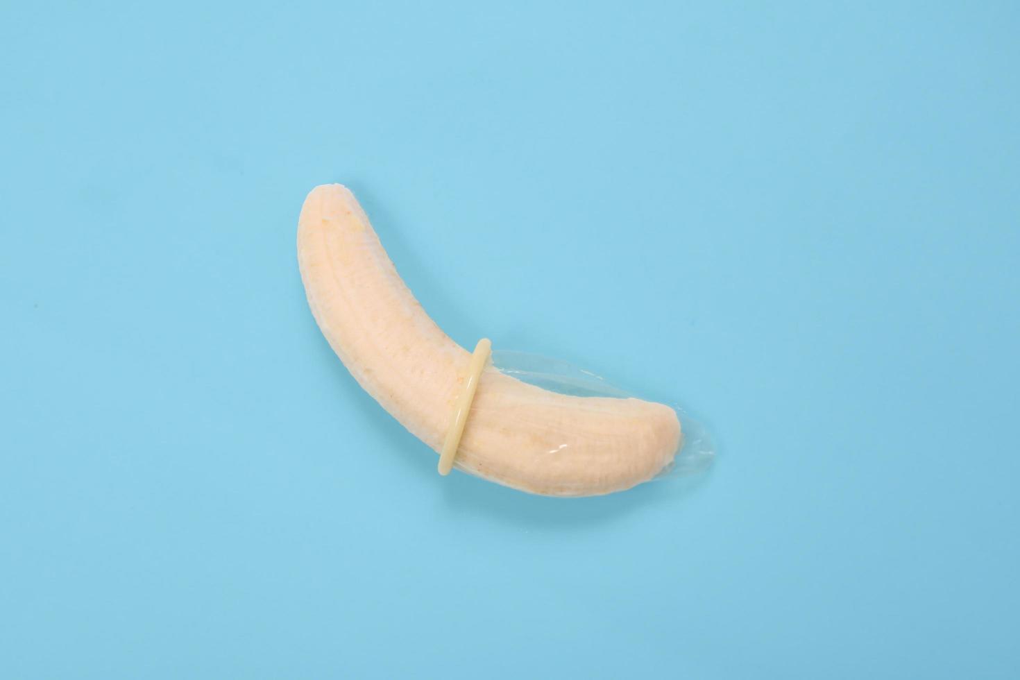 éducation sexuelle avec banane et préservatif isolé sur fond bleu photo