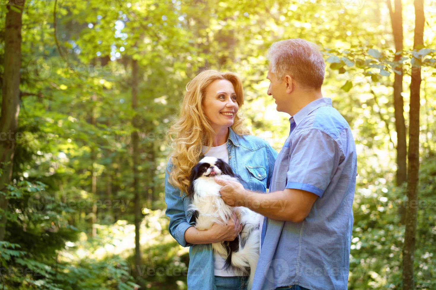 famille mature heureuse avec un chien marchant dans le parc. photo