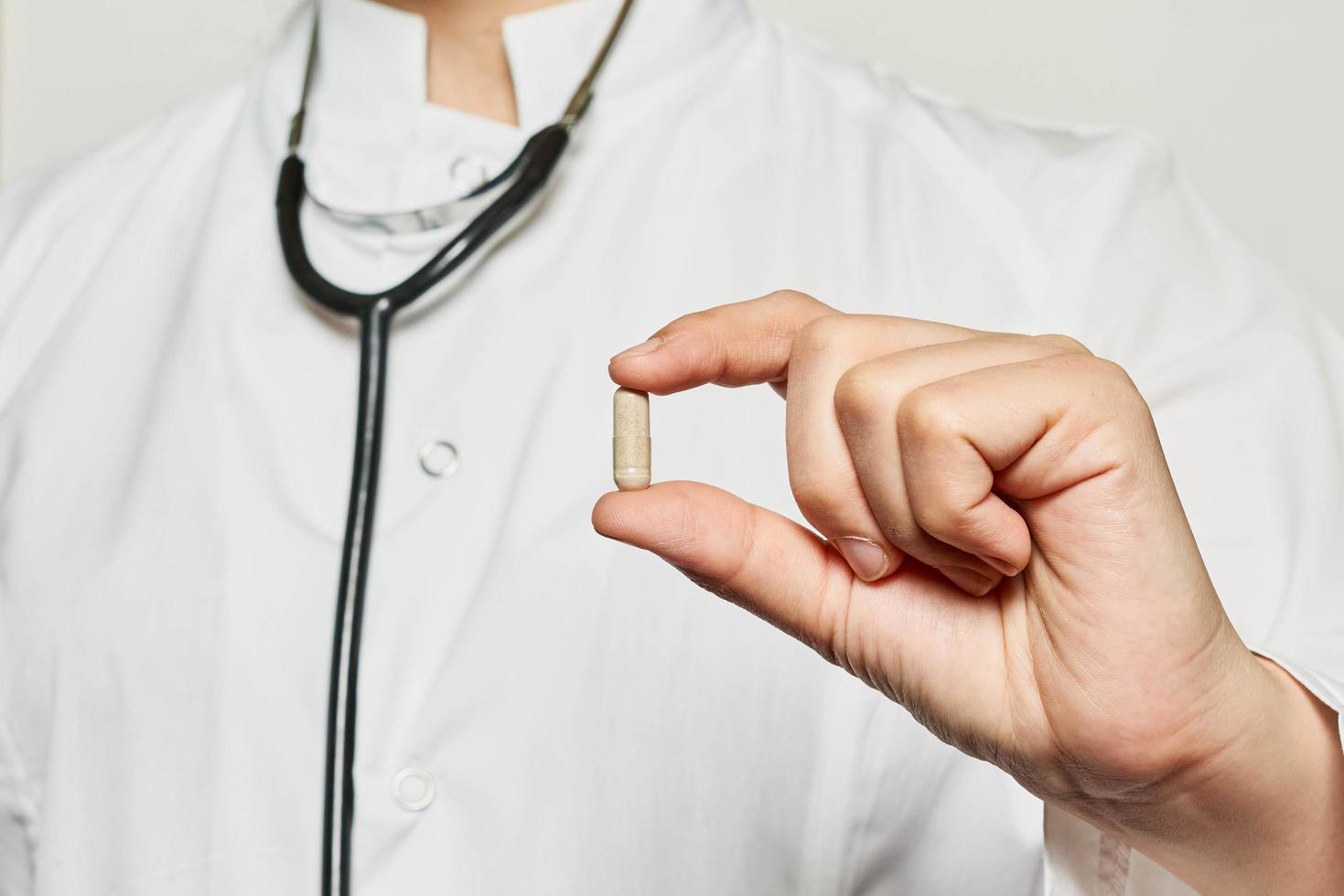 une main de médecin tient une pilule photo