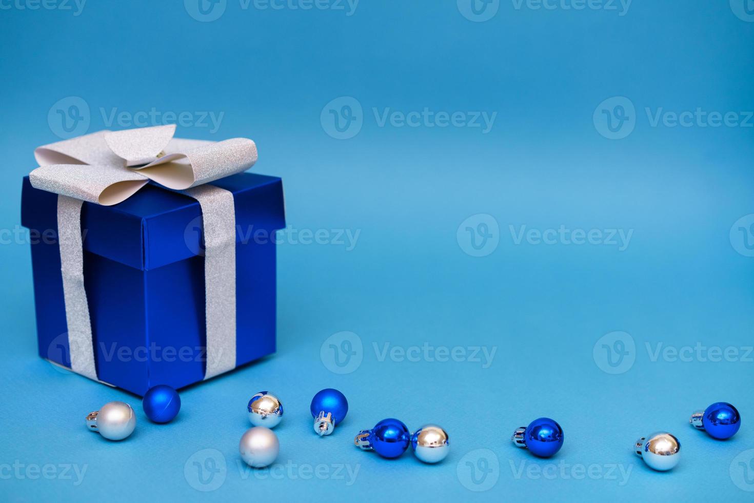 coffret cadeau bleu avec des boules de noël sur fond bleu photo