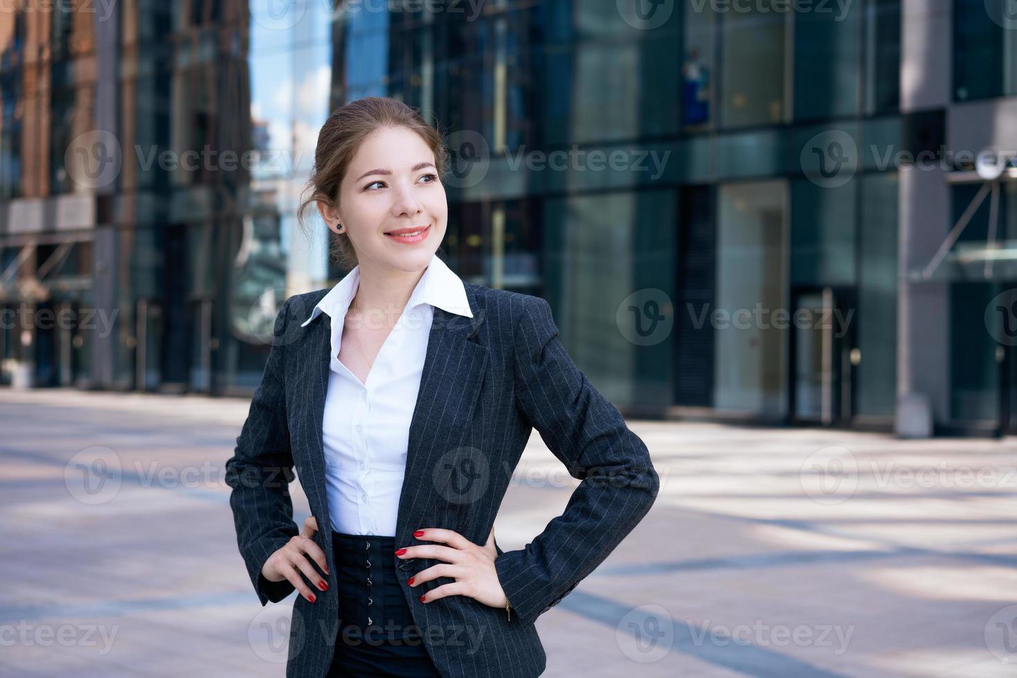 jeune femme se tient avec confiance et sourit à l'extérieur. photo