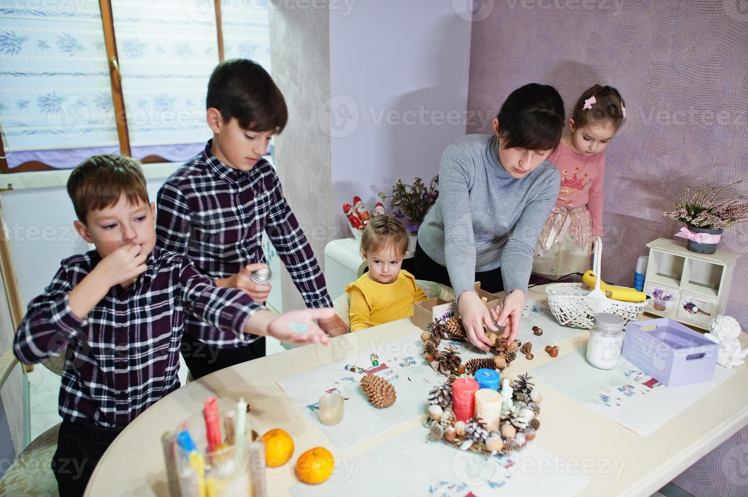 une mère de quatre enfants fabrique une couronne pour le réveillon de noël et fait de la décoration artisanale. Célébration du nouvel an. photo