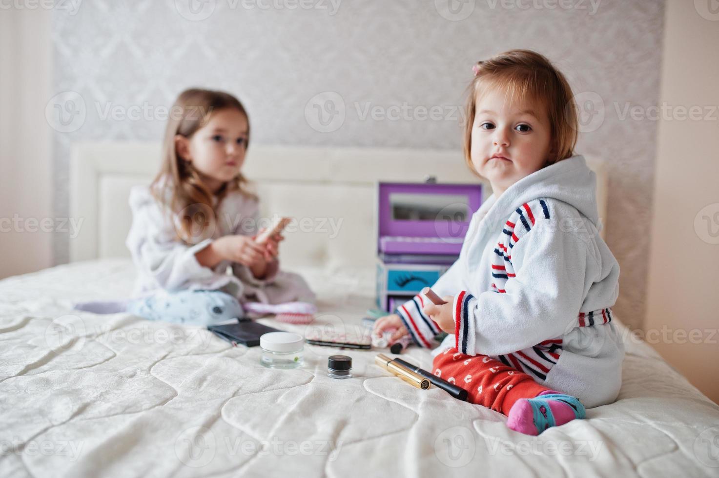 deux sœurs filles se maquillent sur le lit dans la chambre. photo