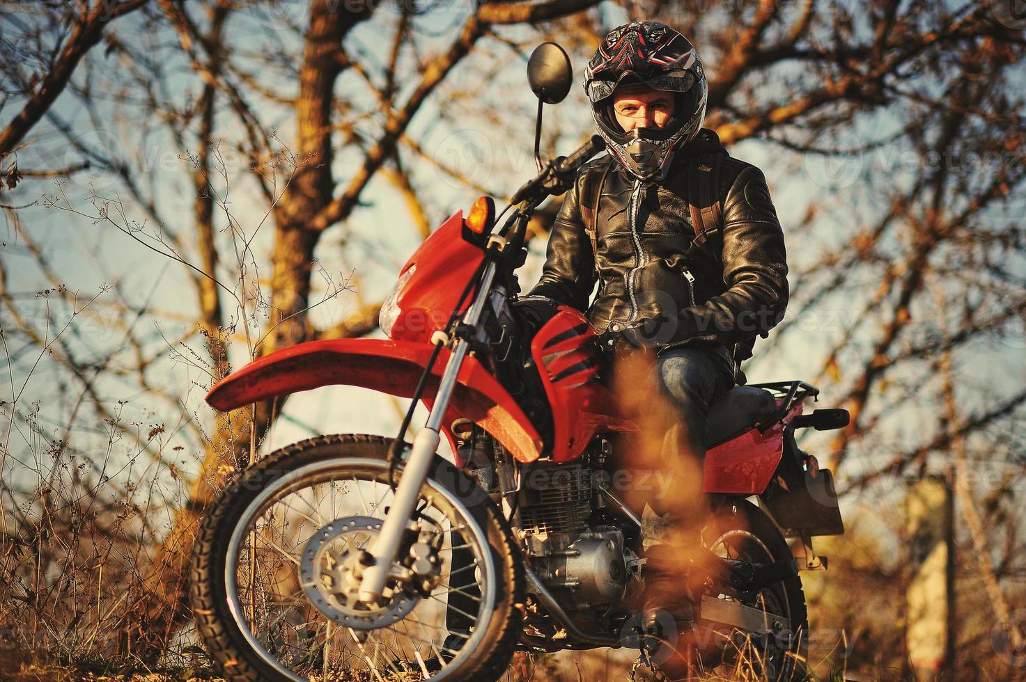 un motard reste au coucher du soleil avec lui un vélo d'enduro photo