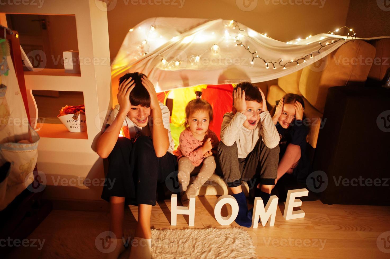 les enfants dans la tente regardent la télévision la nuit à la maison. humeur hygge. photo