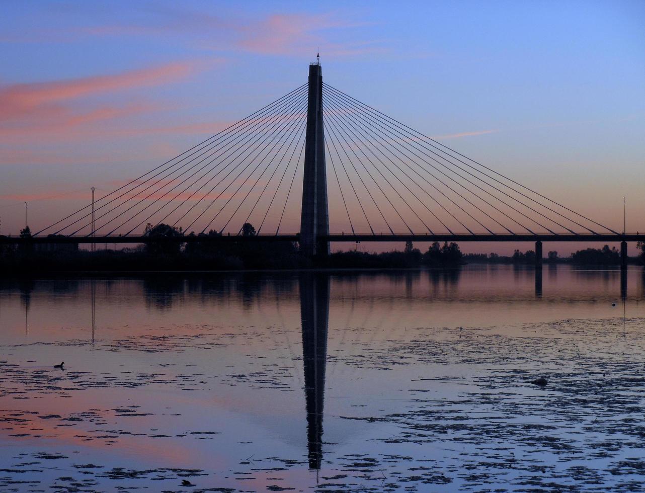 coucher de soleil sur le pont au dessus de la rivière photo