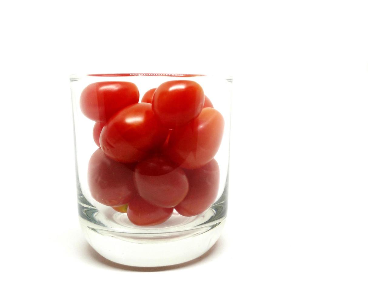 Tomates cerises en verre isolé sur fond blanc photo