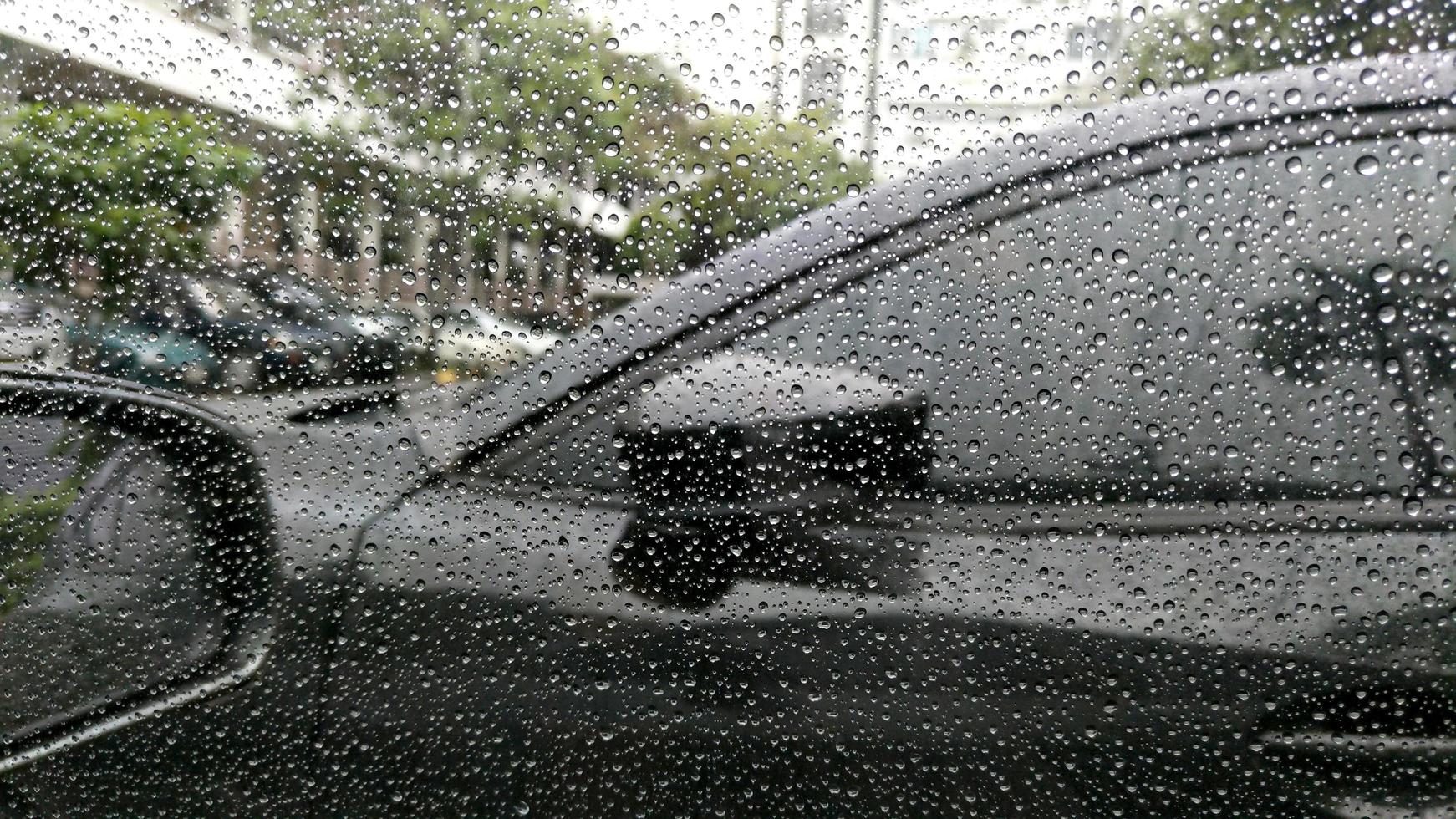 gouttes de pluie sur la fenêtre avec fond de voiture. photo