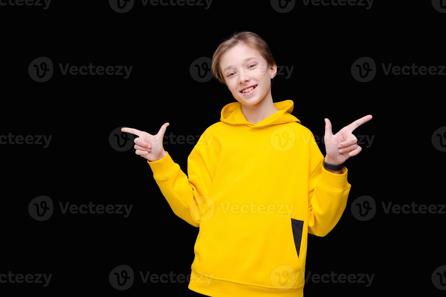 jeune homme souriant heureux et joyeux en sweat-shirt jaune vif pointant photo