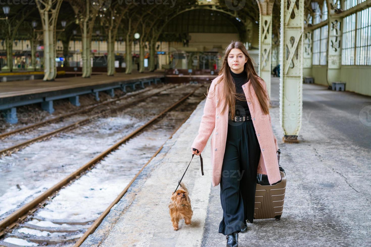 bâtiment de gare vide. jeune femme passagère se tient avec une valise et un petit photo