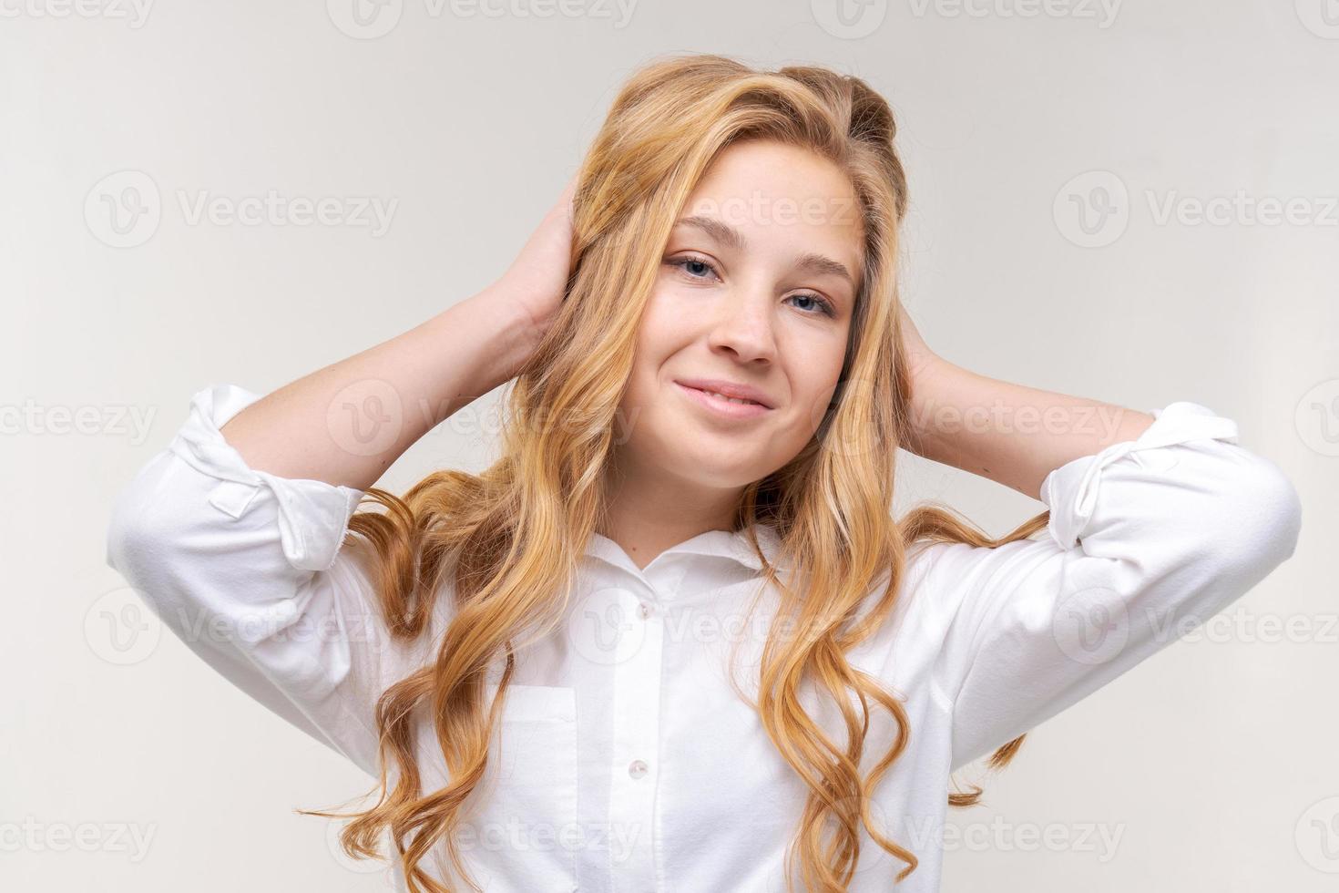 photo d'une jeune femme blonde optimiste touche ses longs cheveux avec ses mains