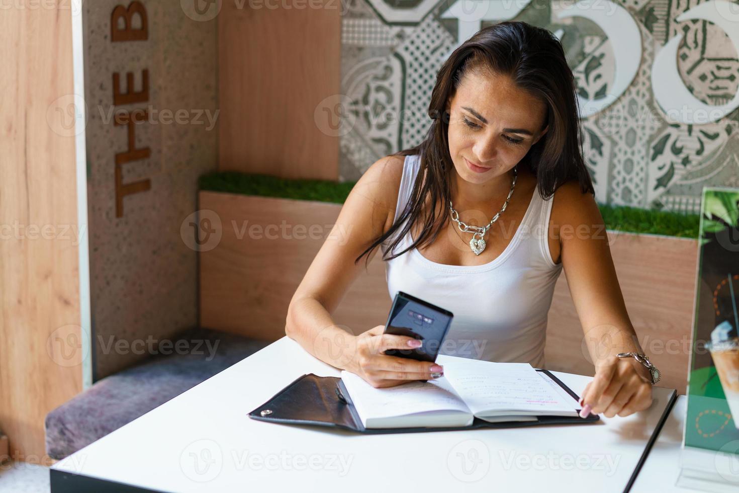 jeune femme assise dans un café à table et tapant un message sur le smartphone. photo