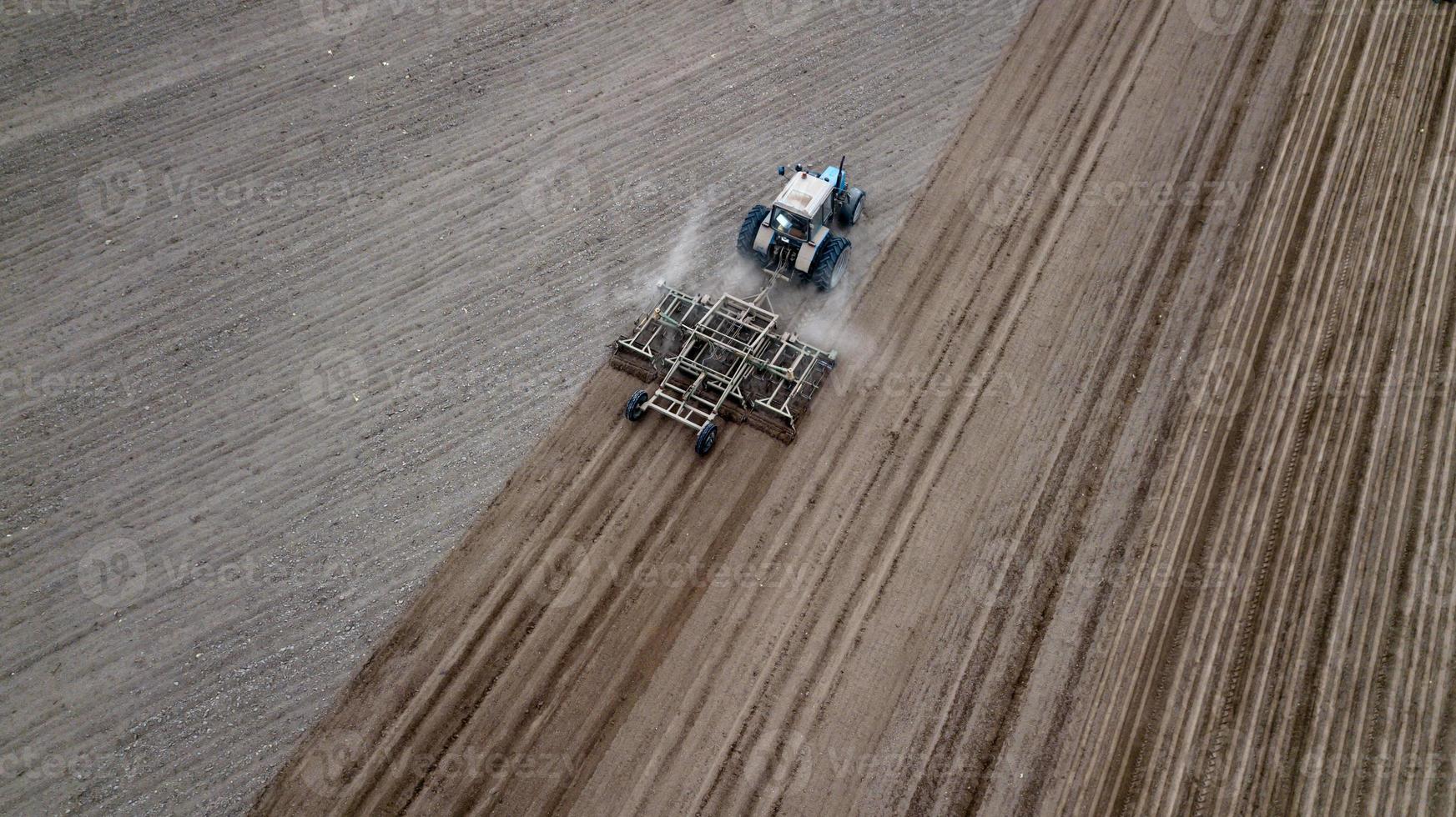 vue aérienne de dessus d'un tracteur, moissonneuse-batteuse labourant des terres agricoles au printemps photo