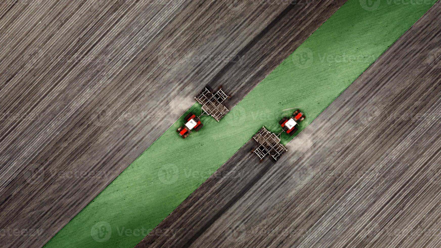 vue aérienne de dessus d'un tracteur, moissonneuse-batteuse labourant des terres agricoles au printemps photo