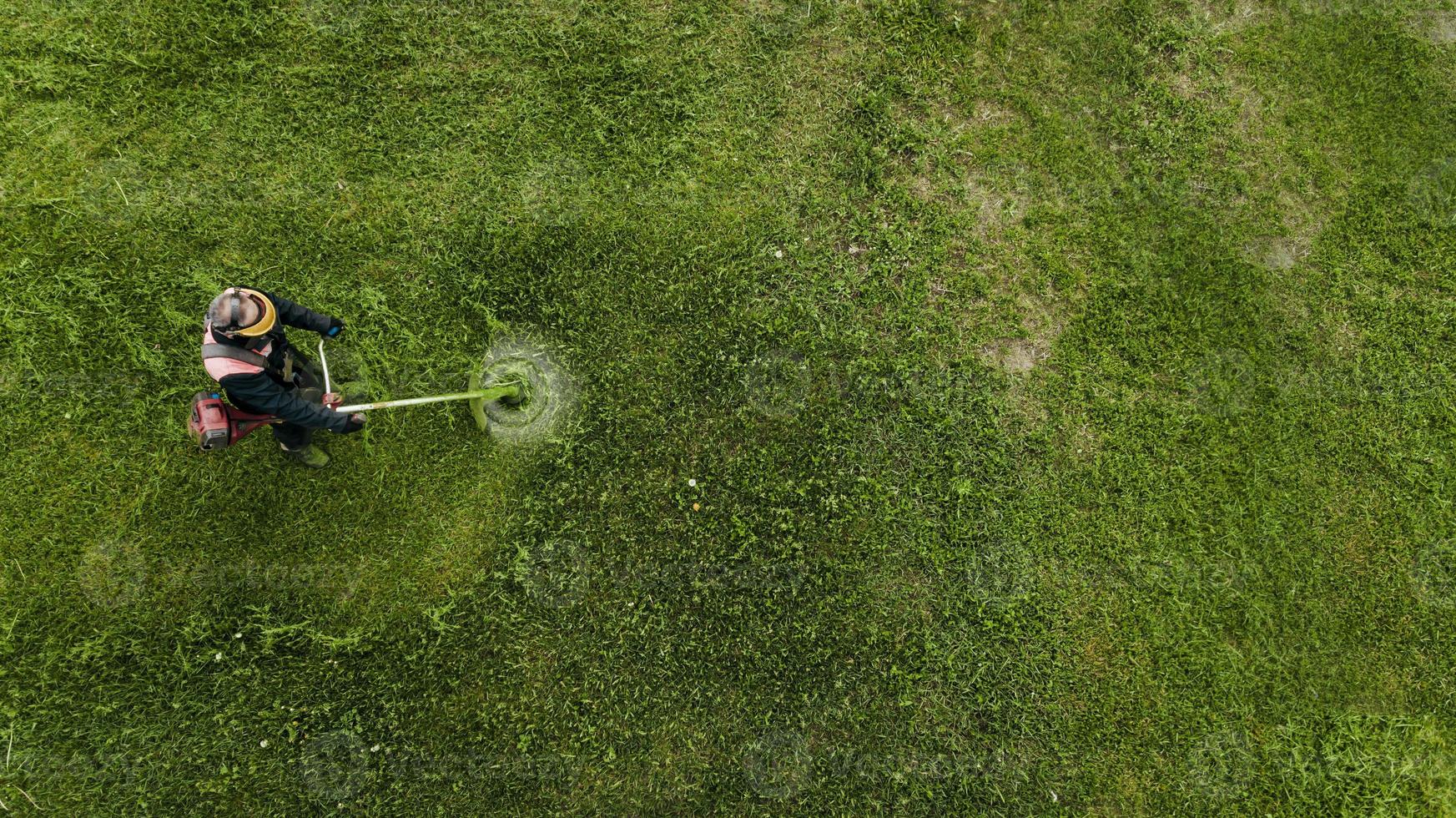 vue de dessus homme ouvrier coupant de l'herbe avec une tondeuse à gazon. photo