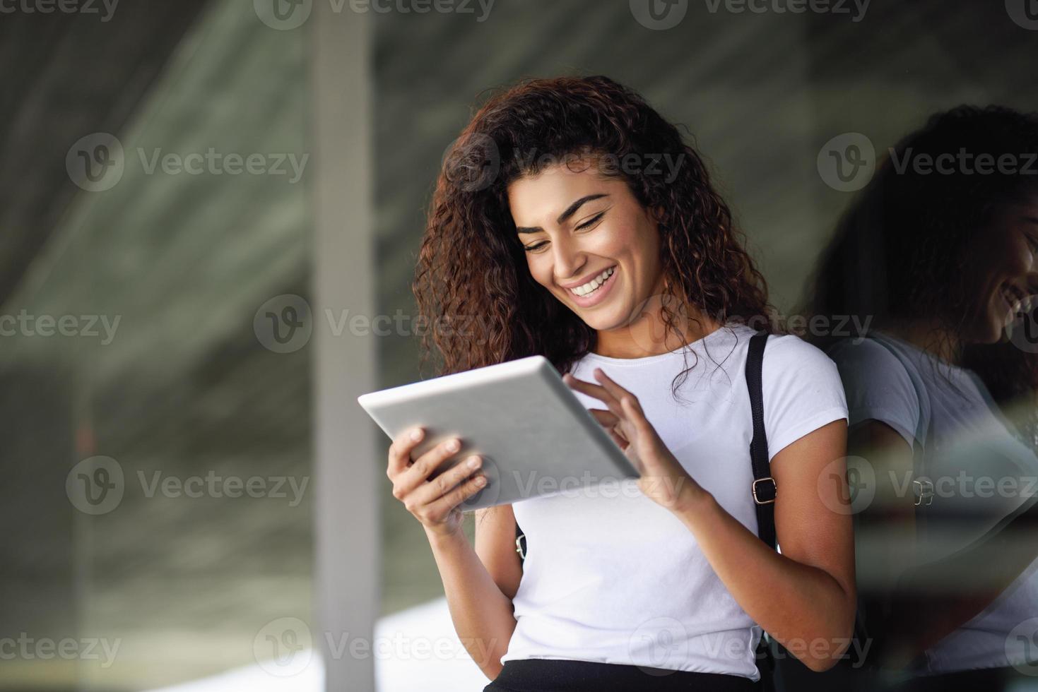 fille arabe souriante à l'aide d'une tablette numérique dans le contexte des affaires. photo