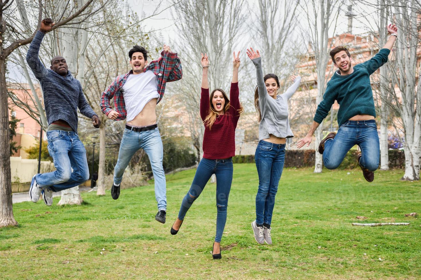 groupe de jeunes sautant ensemble à l'extérieur photo