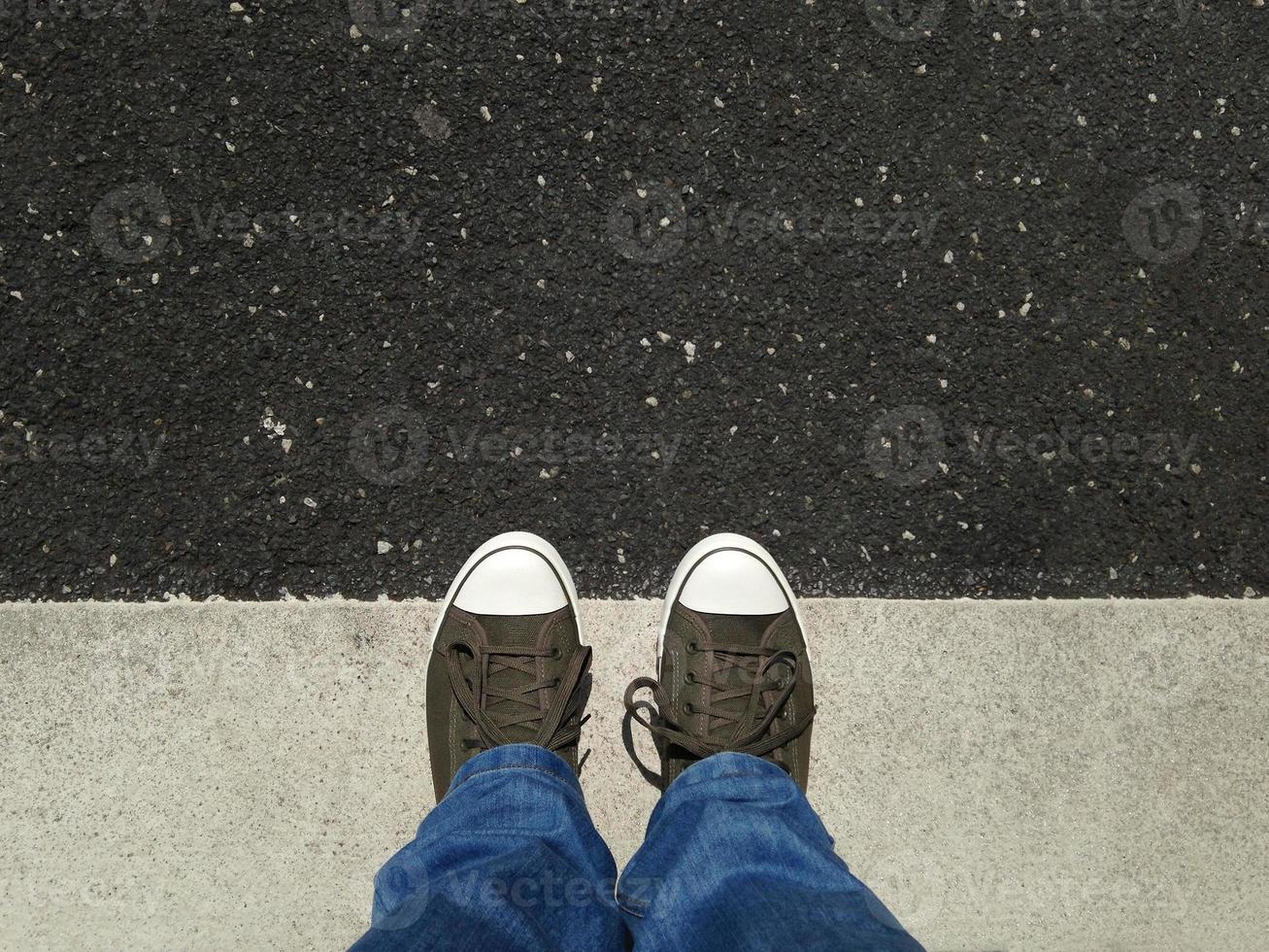 pieds dans des chaussures de toile debout sur l'asphalte aligné avec le marquage routier photo