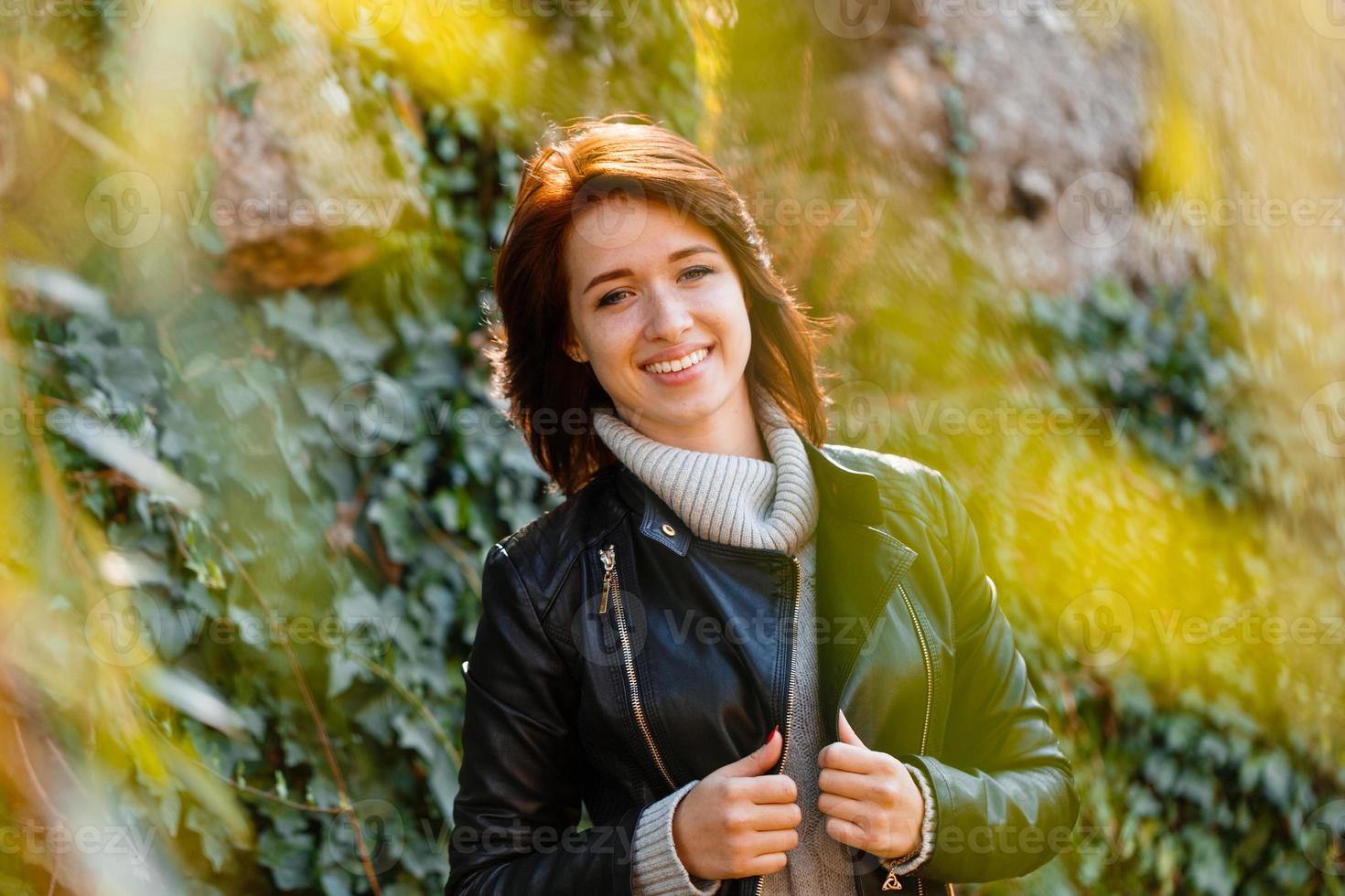 belle jeune femme aux cheveux châtain clair dans un pull gris et cuir noir photo