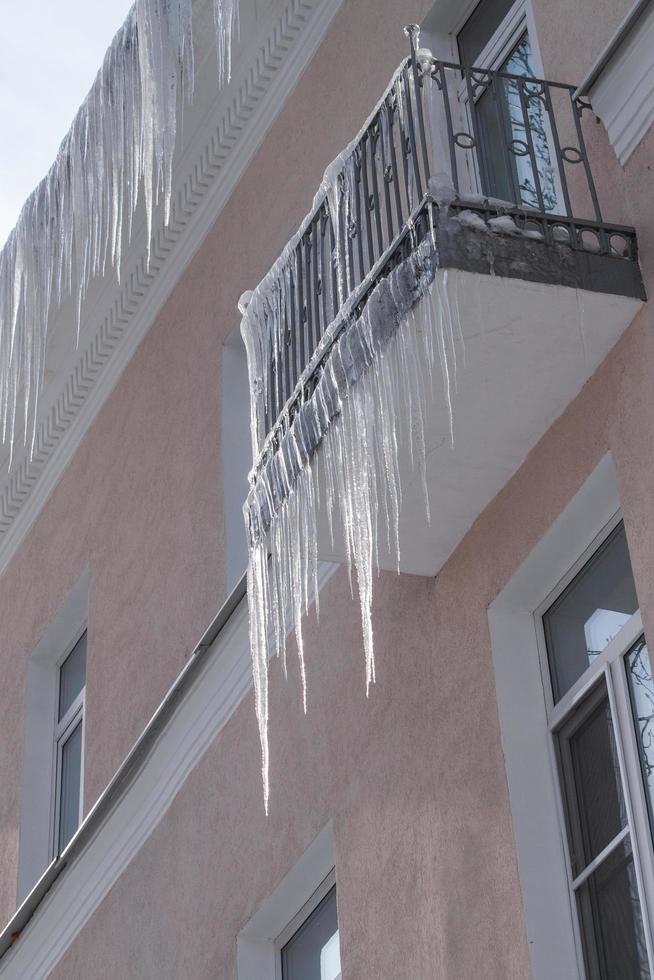 vue de bas en haut des glaçons pointus dangereux suspendus au toit et au balcon. photo