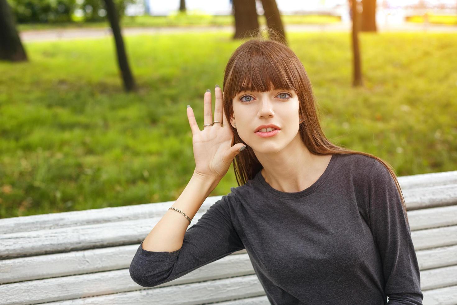 jeune femme dans un parc tenant une main près de votre oreille, le concept d'écoute clandestine photo