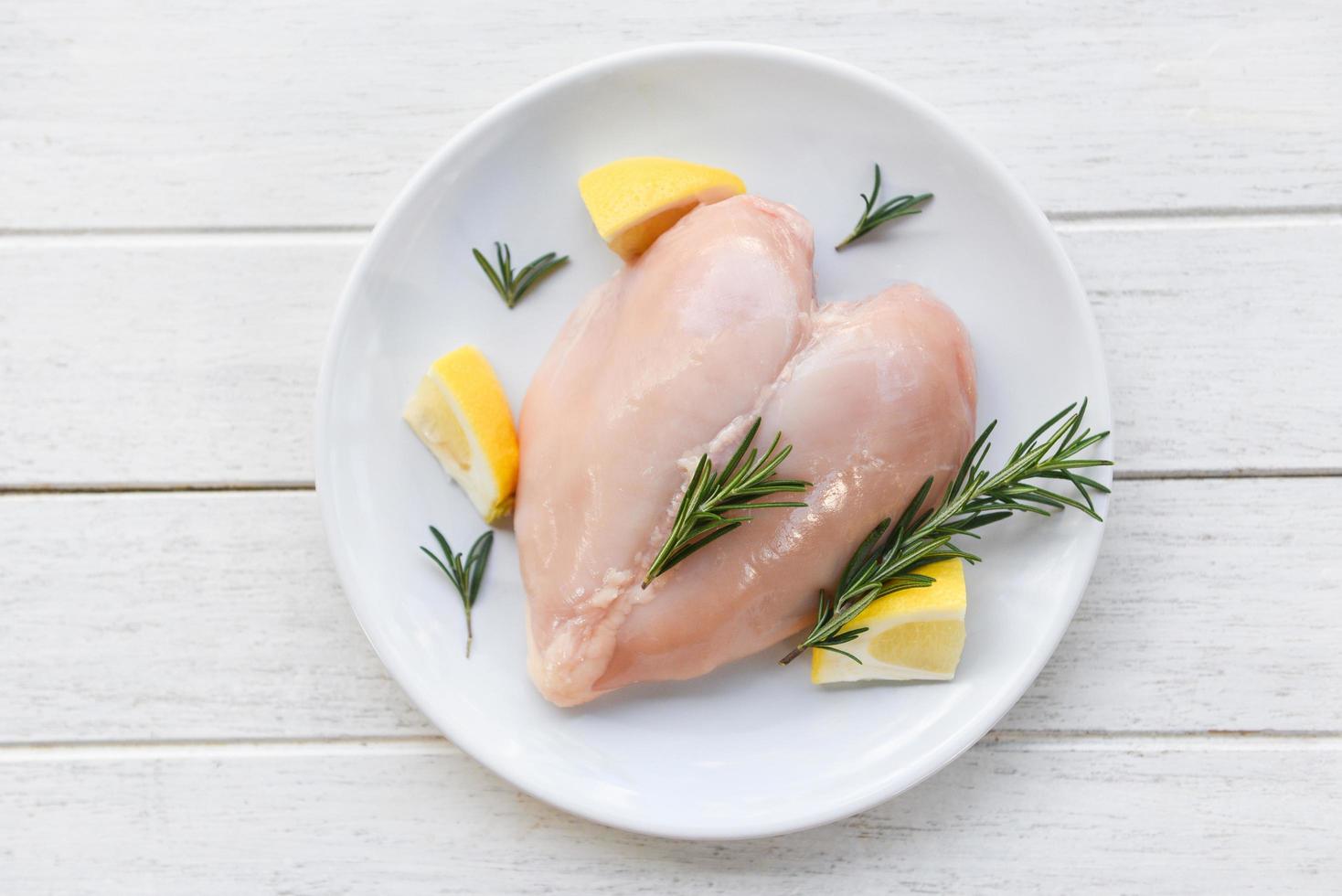 viande de poulet crue au romarin et au citron filet de poitrine de poulet cru frais en forme de coeur sur plaque blanche photo