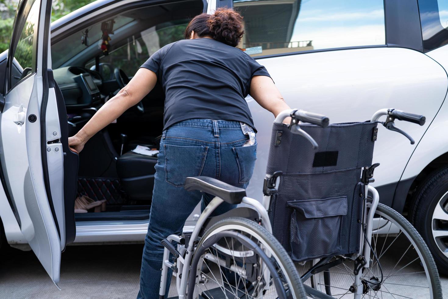 femme asiatique pliant et soulevant le fauteuil roulant dans sa voiture. notion d'accessibilité. photo