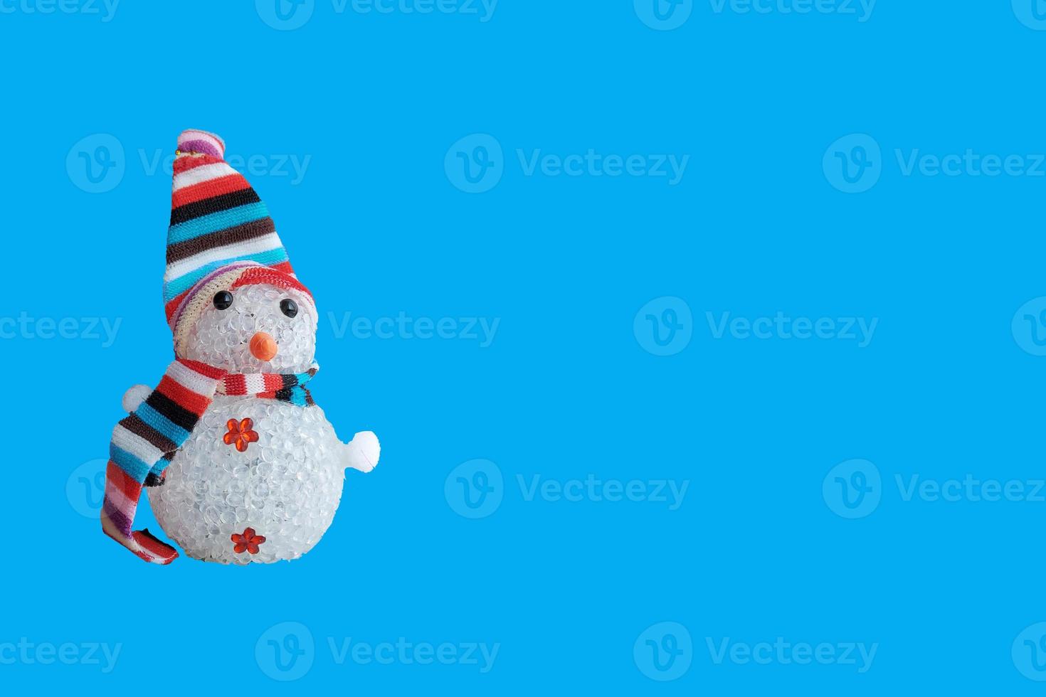 bonhomme de neige dans un chapeau et une écharpe rayés isolés sur fond bleu. bannière de décoration de noël horizontale, place pour le texte. nouvel an, vacances photo