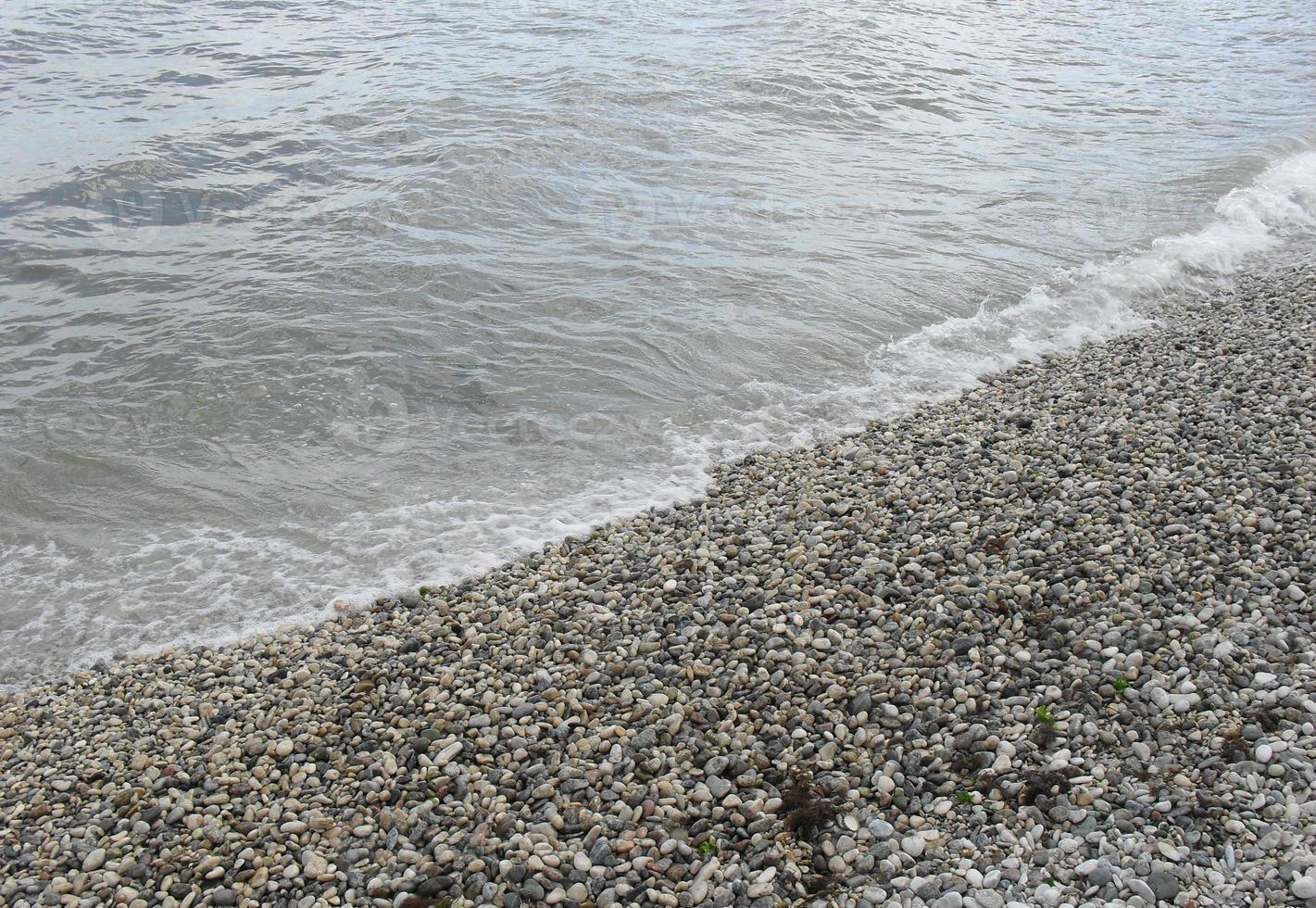 vague de mer avec de la mousse sur le rivage avec des cailloux. fond, bannière, été, voyage photo