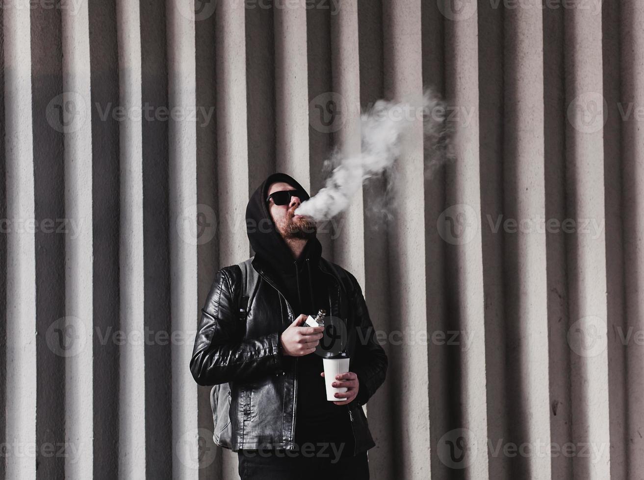 un homme barbu cool fume des cigarettes électroniques photo