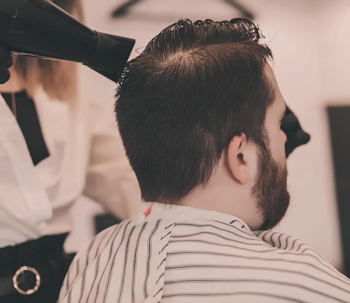 le barbier sèche la tête de l'homme photo